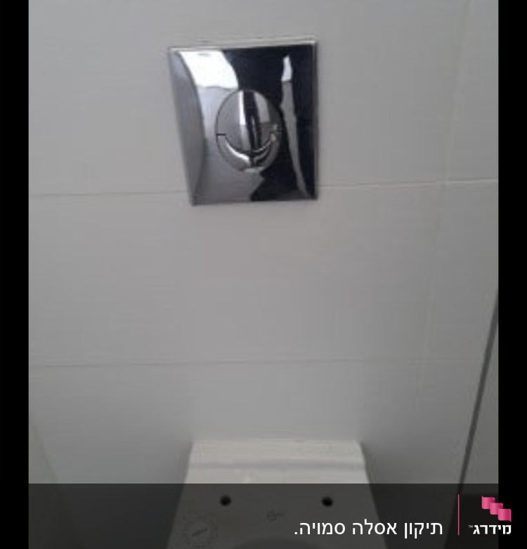אסלה עם לחצן הדחה על קיר אריחים לבן